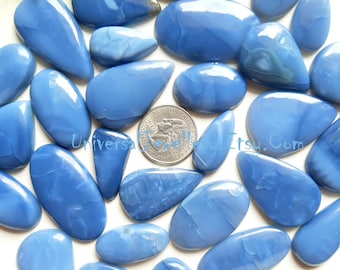 May include: A collection of polished, light blue opal gemstones in various shapes, including teardrops and ovals. The stones have a smooth, glossy surface with subtle internal patterns. A quarter coin is included for size reference. The background is a light color.