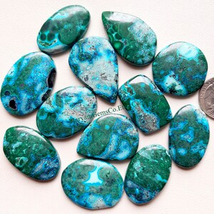 May include: Ten turquoise, green, and blue chrysocolla cabochons with a marbled pattern. The cabochons are oval shaped and have a smooth, polished finish.