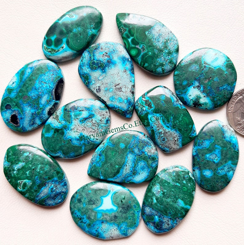 May include: Ten turquoise, green, and blue chrysocolla cabochons with a marbled pattern. The cabochons are oval shaped and have a smooth, polished finish.