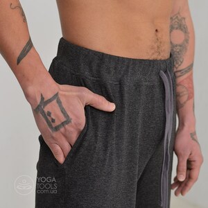 K&ouml;nnte beinhalten: Eine dunkelgraue Jogginghose mit Kordelzugbund und einer Tasche an der Seite. Die Jogginghose ist aus einem weichen, bequemen Stoff.