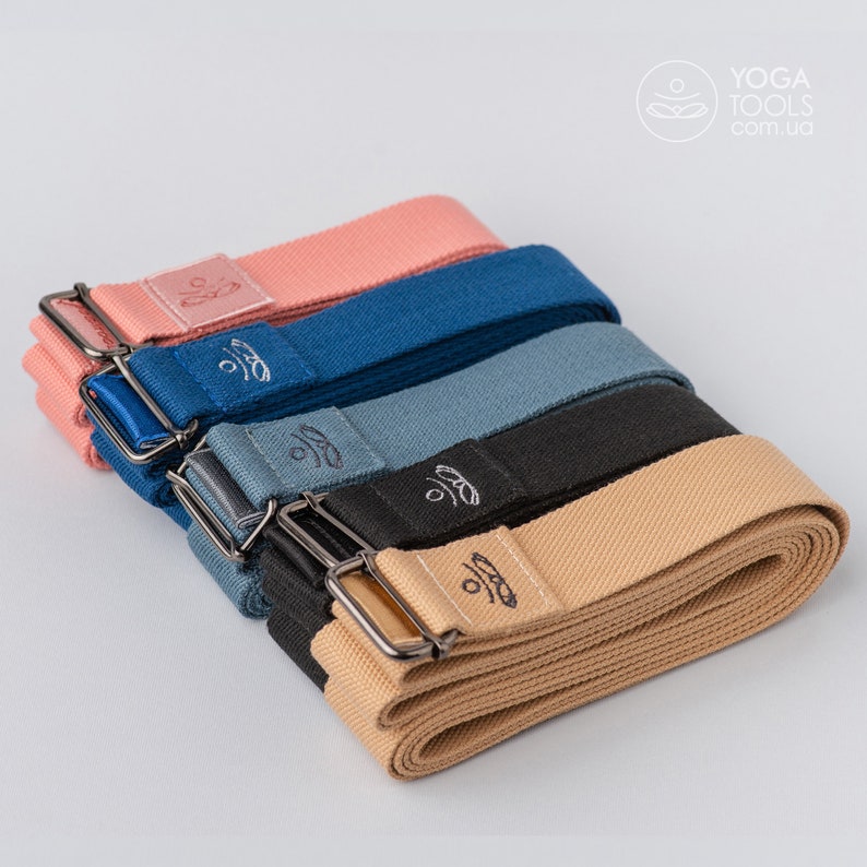 May include: Five yoga straps in different colors, stacked on top of each other. The straps are made of cotton and have a metal buckle. The straps are labeled with the text "Yoga Tools" and the website address "com.ua".