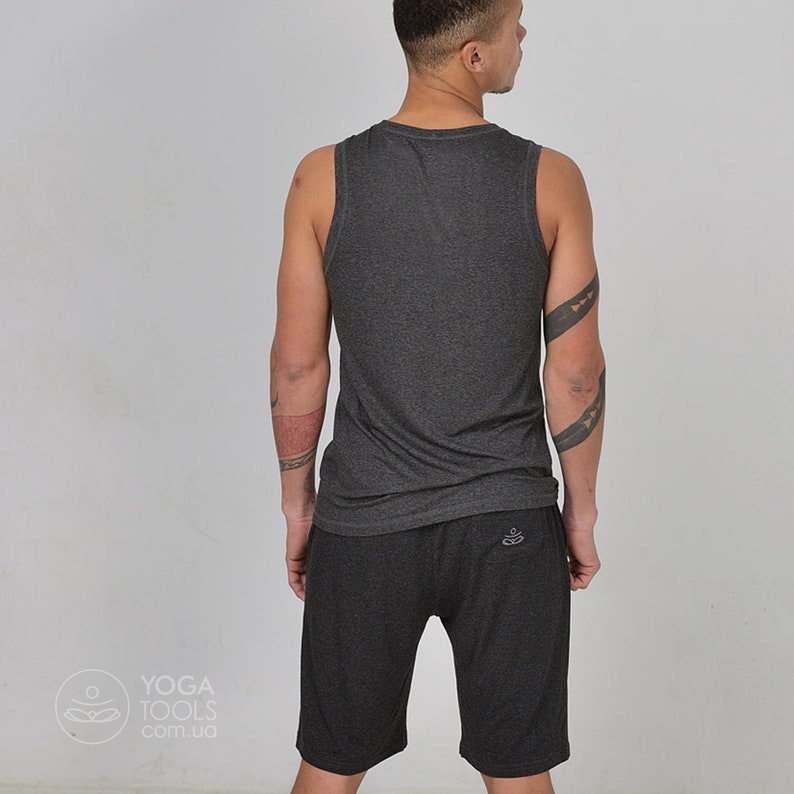 K&ouml;nnte beinhalten: Ein dunkelgraues &auml;rmelloses Tanktop und passende Shorts. Die Shorts haben ein kleines Logo auf der Ges&auml;&szlig;tasche.