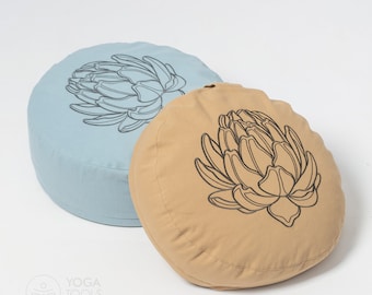 May include: Two round meditation cushions, one light blue and one beige, with a black outline of an artichoke flower design on each.
