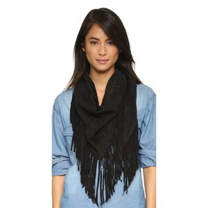 May include: A black suede scarf with fringe and cutouts. The scarf is worn by a person with long dark hair.
