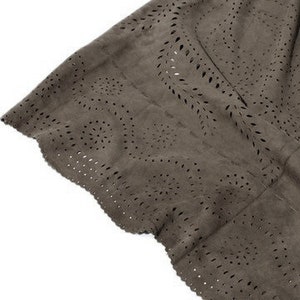 May include: Close-up of a brown suede skirt with a scalloped hem and a cut-out pattern.