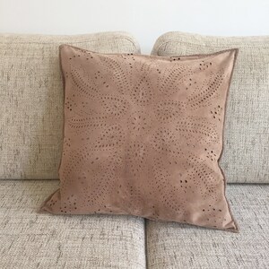 May include: A brown suede cushion with a cut-out design of swirling circles and dots.