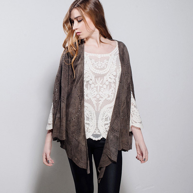 May include: A brown suede jacket with cutouts and a lace overlay. The jacket has a long, flowing silhouette and a relaxed fit.