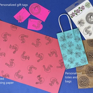 May include: A set of personalized gift tags, totes, and bags featuring a bird and sun design. The tags are pink and white, the tote is blue, and the bag is brown.