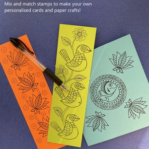 May include: Three paper craft stamps with black ink designs on a blue background. The stamps feature a bird, a lotus flower, and a fish in a circle.