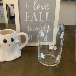 May include: A white ghost mug and a clear glass with white ghost decals. A framed sign behind the mugs reads "i love fall most of all".
