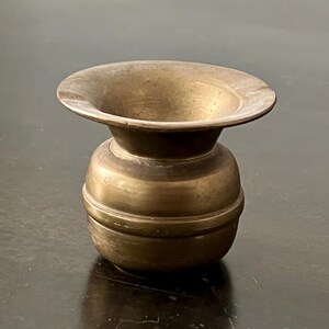 May include: A vintage brass ashtray with a wide, shallow bowl and a rounded base. The ashtray has a warm, antique finish and a classic design, suitable for home decor or a collector's item.
