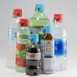 May include: Assortment of bottled beverages, including water, soda, and tea, each secured with a red and blue bottle lock. The bottles vary in size and brand, with labels visible. The locks appear to be a security measure.