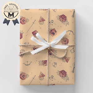 May include: Gift wrapped in tan paper with a repeating pattern of dice, swords, and floral accents. The package is tied with twine and a white bow. A sticker with the text "FREE SHIPPING" is visible.