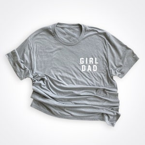 May include: A gray t-shirt with the text "GIRL DAD" printed in white on the front.