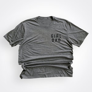 May include: A heather gray t-shirt with the text "GIRL DAD" printed on the front.