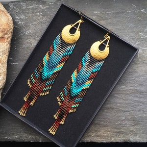 May include: A pair of long, beaded earrings with a gold-toned disc at the top. The earrings are made with brown, black, blue, and turquoise beads.
