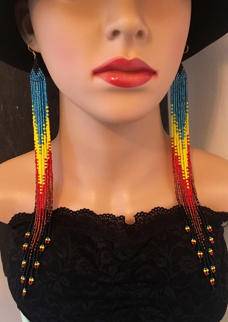 May include: Long beaded earrings with a gradient of red, yellow, blue, and black beads. The earrings are hanging from a person's ears.