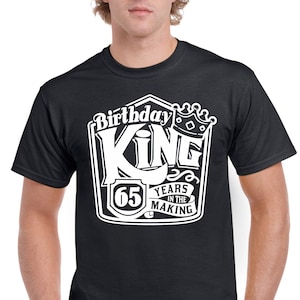 May include: Black t-shirt with a white graphic design that says "Birthday King 65 Years in the Making" with a crown above the word "King".