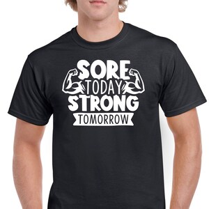 May include: Black t-shirt with white text that reads "Sore Today Strong Tomorrow" with a graphic of two white bicep muscles.