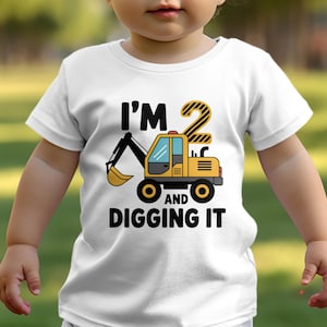 May include: A white t-shirt with a yellow construction vehicle graphic and the text "I'm 2 and digging it".