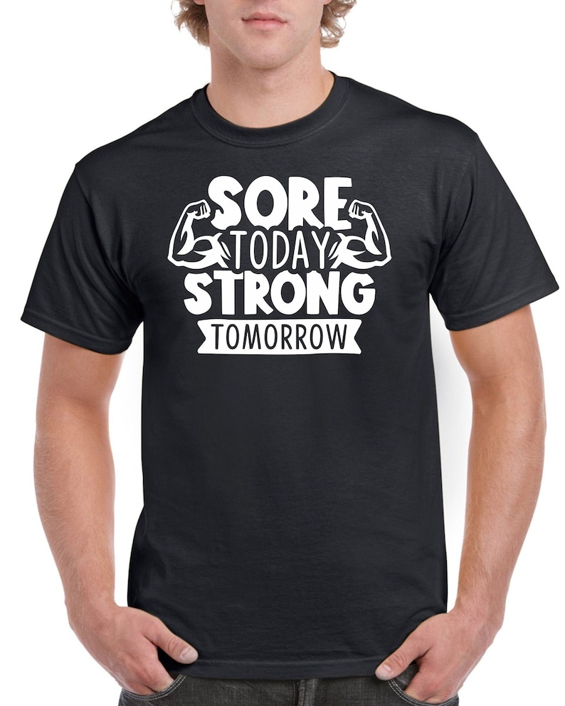May include: Black t-shirt with white text that reads "Sore Today Strong Tomorrow" with a graphic of two white bicep muscles.