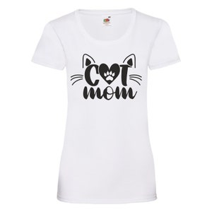 Peut inclure: T-shirt blanc avec un motif noir repr&eacute;sentant un visage de chat avec un c&oelig;ur et une empreinte de patte &agrave; l'int&eacute;rieur du c&oelig;ur et le texte "Cat Mom" en dessous.