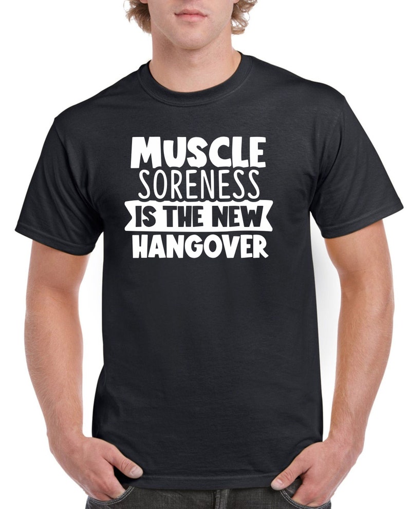 May include: Black t-shirt with white text that reads "Muscle Soreness is the New Hangover".