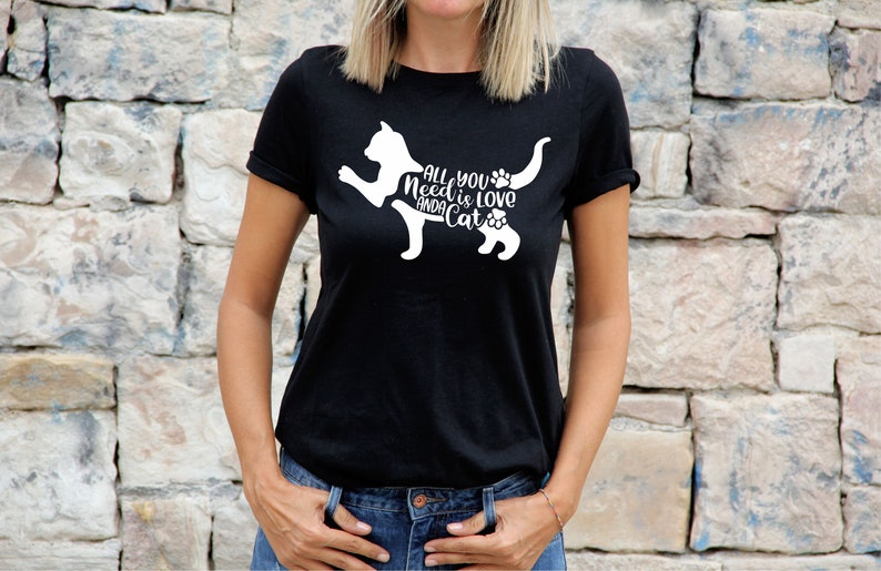 May include: Black t-shirt with a white silhouette of a cat and the text "All you need is love and a cat".