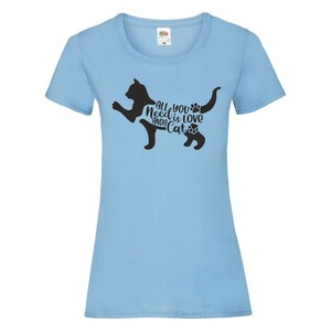 May include: Light blue t-shirt with a black silhouette of a cat and the text "All you need is love and a cat" with paw prints.