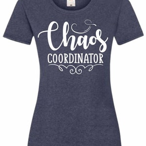 May include: A navy blue t-shirt with white text that reads "Chaos Coordinator" with a decorative flourish above and below the text.