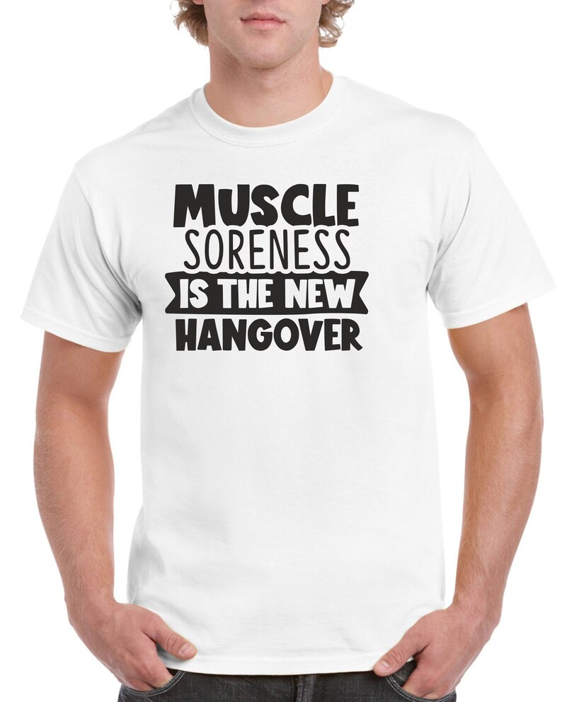 May include: White t-shirt with black text that reads "Muscle Soreness Is The New Hangover".