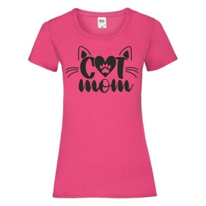 Peut inclure: T-shirt rose avec une silhouette de chat noire et le texte "Cat Mom" avec une empreinte de patte dans le c&oelig;ur.