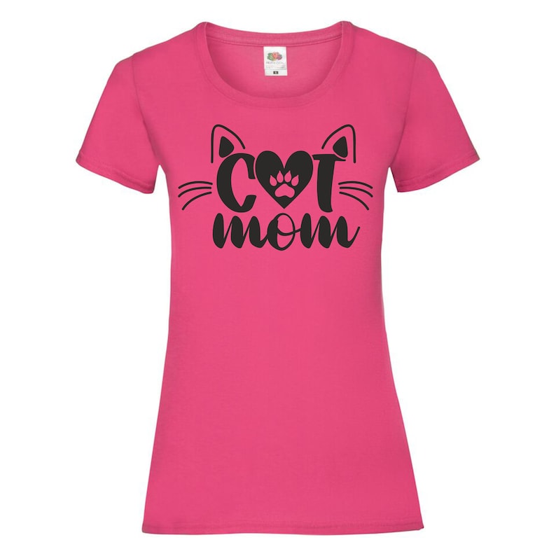 Peut inclure: T-shirt rose avec une silhouette de chat noire et le texte "Cat Mom" avec une empreinte de patte dans le c&oelig;ur.