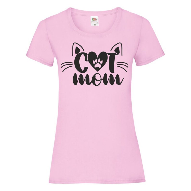 Peut inclure: T-shirt rose avec un motif noir repr&eacute;sentant un visage de chat avec un c&oelig;ur et une empreinte de patte au milieu et le texte "Cat Mom" en dessous.