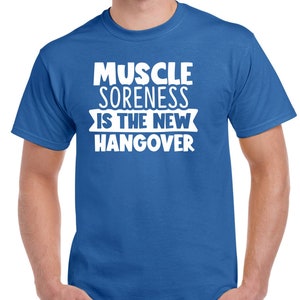 May include: A royal blue t-shirt with white text that reads "Muscle Soreness Is The New Hangover".