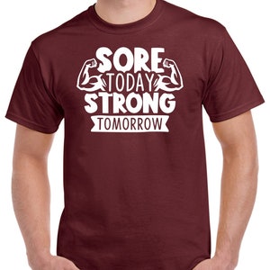 May include: A maroon t-shirt with white text that reads "Sore Today Strong Tomorrow" with a graphic of two bicep muscles.