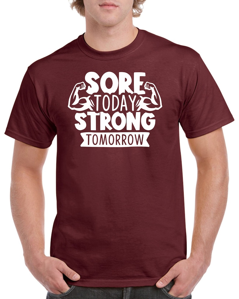 May include: A maroon t-shirt with white text that reads "Sore Today Strong Tomorrow" with a graphic of two bicep muscles.