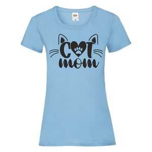 Peut inclure: T-shirt bleu clair avec un motif de visage de chat noir et le texte "Cat Mom" avec une empreinte de patte dans le c&oelig;ur.