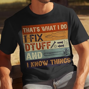 May include: A black t-shirt with a vintage-style graphic that says "That's what I do I fix stuff and I know things". The graphic features tools such as a wrench, pliers, and screws.