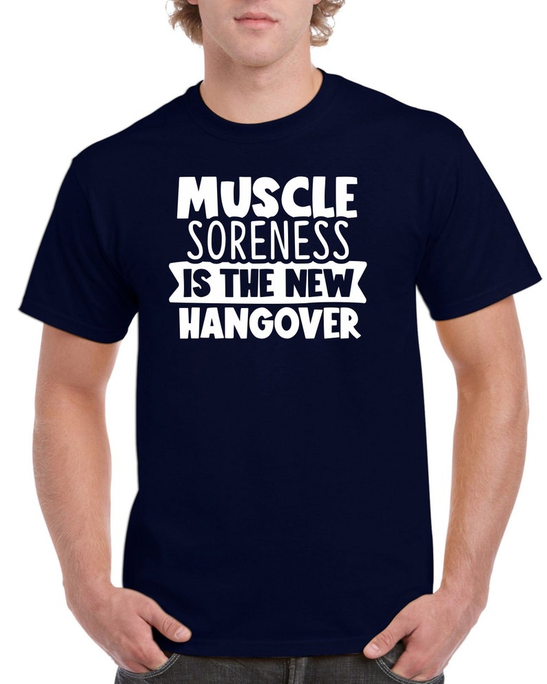 May include: A navy blue t-shirt with white text that reads "Muscle Soreness Is The New Hangover".