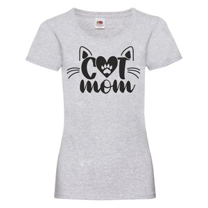 Peut inclure: T-shirt gris avec un motif de visage de chat noir et le texte "Cat Mom" avec une empreinte de patte dans le c&oelig;ur.