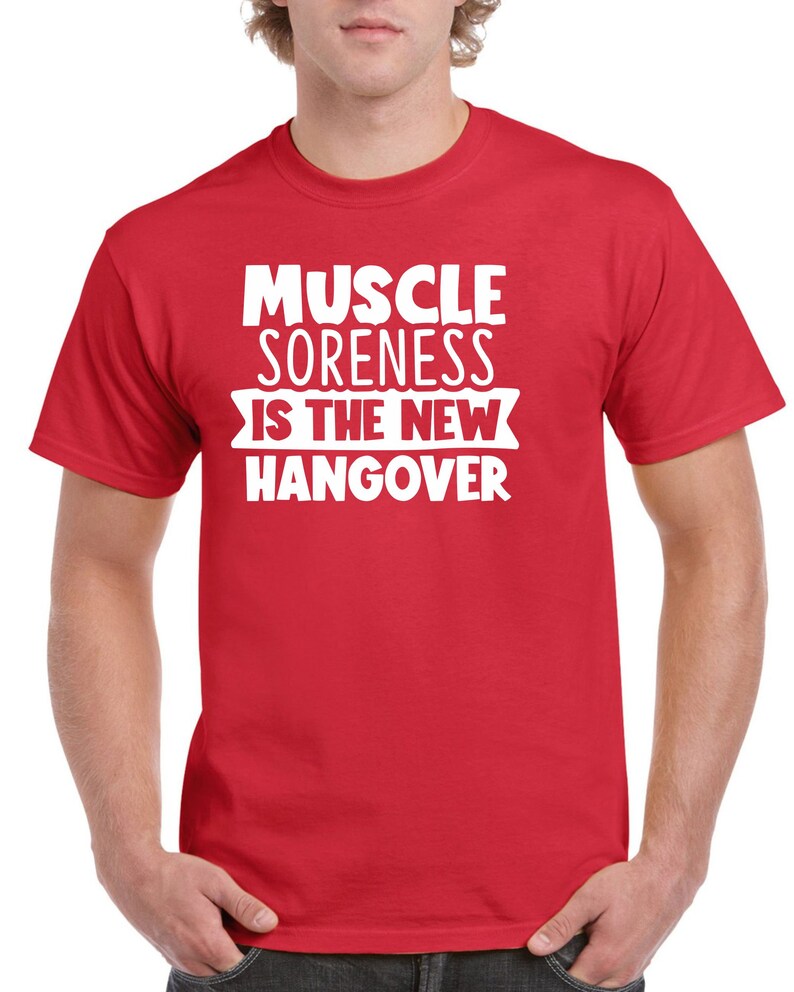 May include: Red t-shirt with white text that reads "Muscle Soreness Is The New Hangover".