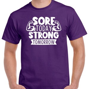 May include: Purple t-shirt with white text that reads "Sore Today Strong Tomorrow" with a graphic of two bicep muscles.