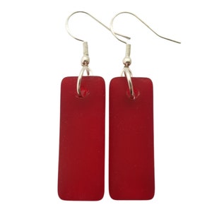 May include: A pair of red rectangular glass earrings with silver hooks.