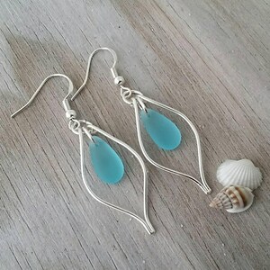 May include: A pair of silver earrings with a teardrop-shaped blue glass bead hanging from each earring.