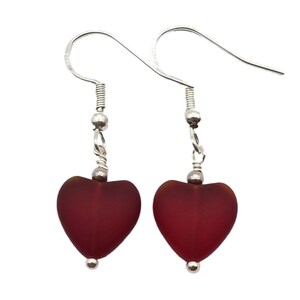 Peut inclure: Une paire de boucles d'oreilles en argent en forme de cœur avec des perles de verre rouges. Les boucles d'oreilles ont un design simple et sont parfaites pour tous les jours.