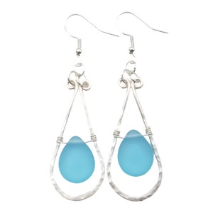 May include: Silver teardrop earrings with a light blue glass bead in each teardrop.