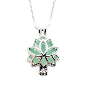 May include: Silver lotus flower charm necklace with a clear green glass insert. The necklace is on a silver chain.