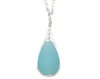 May include: A silver chain necklace with a teardrop-shaped pendant. The pendant is made of wire and holds a light blue sea glass stone.