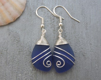 May include: A pair of silver wire wrapped earrings with dark blue glass teardrop shaped pendants.